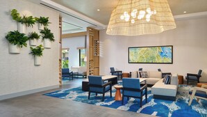 A modern lobby with a large woven light fixture, multiple seating areas, and a map on the wall. - Hyatt House at Ho'opili (Ewa Beach)