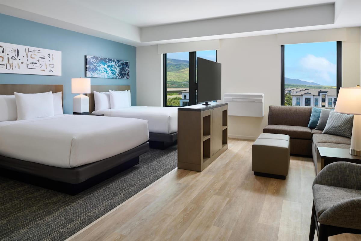 Une chambre d’hôtel avec deux lits, un canapé, une télévision et une vue sur le paysage.