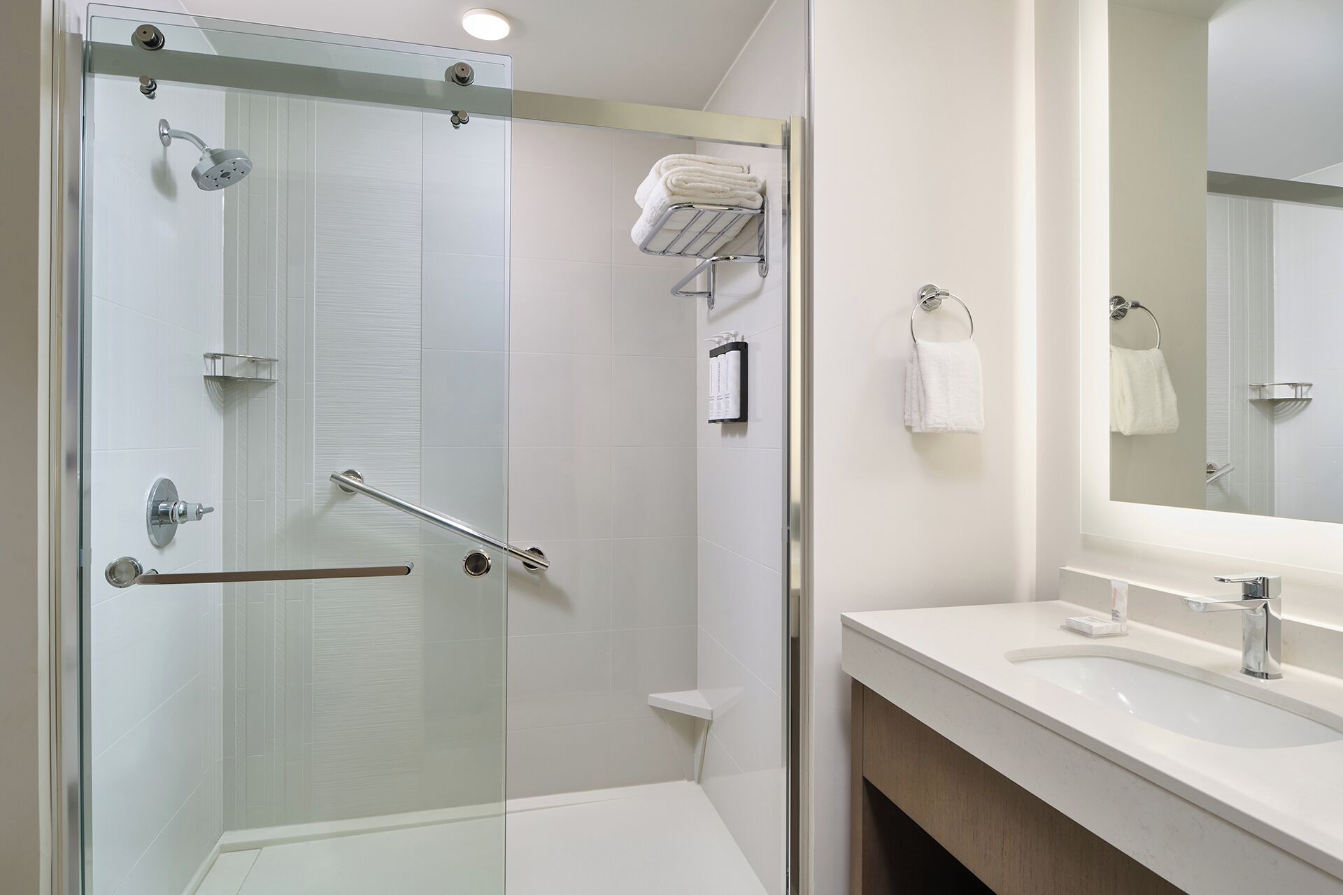 Een moderne badkamer met een douchecabine van glas, een wit wastafelmeubel en een spiegel.