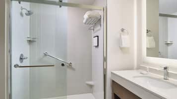 Een moderne badkamer met een douchecabine van glas, een wit wastafelmeubel en een spiegel.