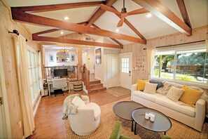 A spacious living area with a white sofa, a coffee table, and a kitchen in the background. - Oak & Vine: Pool | Hot Tub | Fire Table | BBQ (Glen Ellen)
