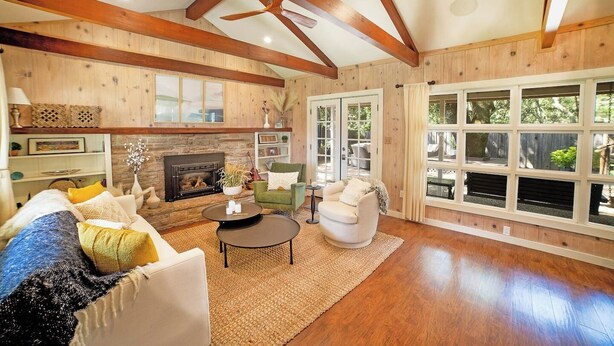A spacious living room with a fireplace, wooden beams, and large windows. - Oak & Vine: Pool | Hot Tub | Fire Table | BBQ (Glen Ellen)