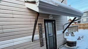 Une façade en bois avec une pancarte indiquant « BIENVENUE », une porte et une boîte aux lettres.
