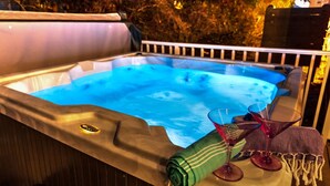 Un jacuzzi con borde de madera, un vaso y una toalla.