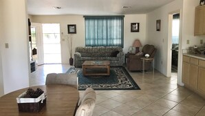 A living room with a sofa, armchair, coffee table, and a dining area with a table and chairs.