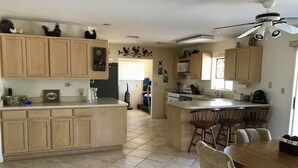 A kitchen with wooden cabinets, a central island, and a dining area with chairs.