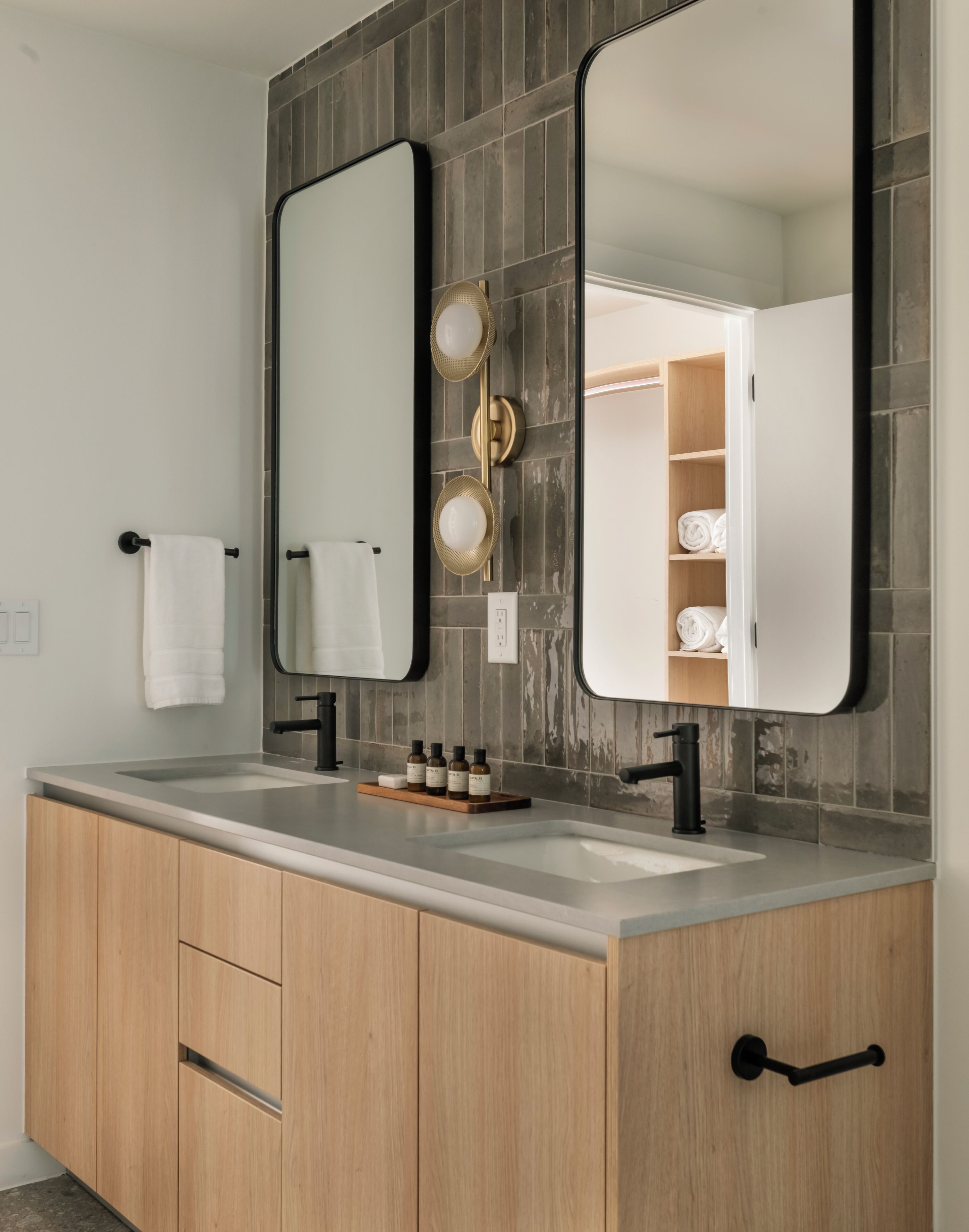 A modern bathroom with two sinks, a large mirror, and a towel rack.