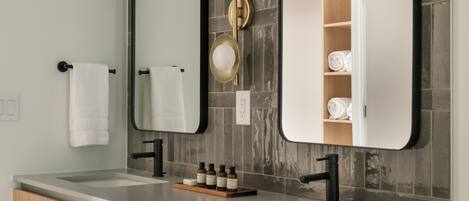 A modern bathroom with two sinks, a large mirror, and a towel rack.
