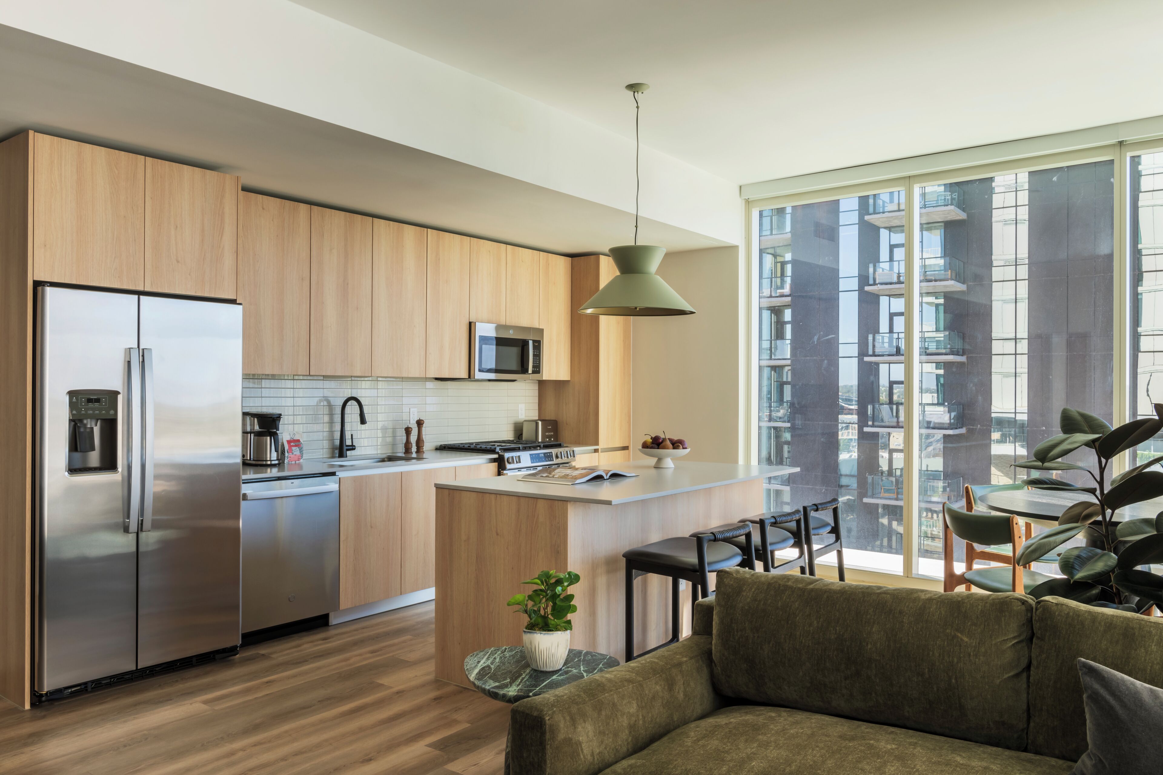 A modern kitchen with stainless steel appliances, a central island, and a view of a high-rise building.