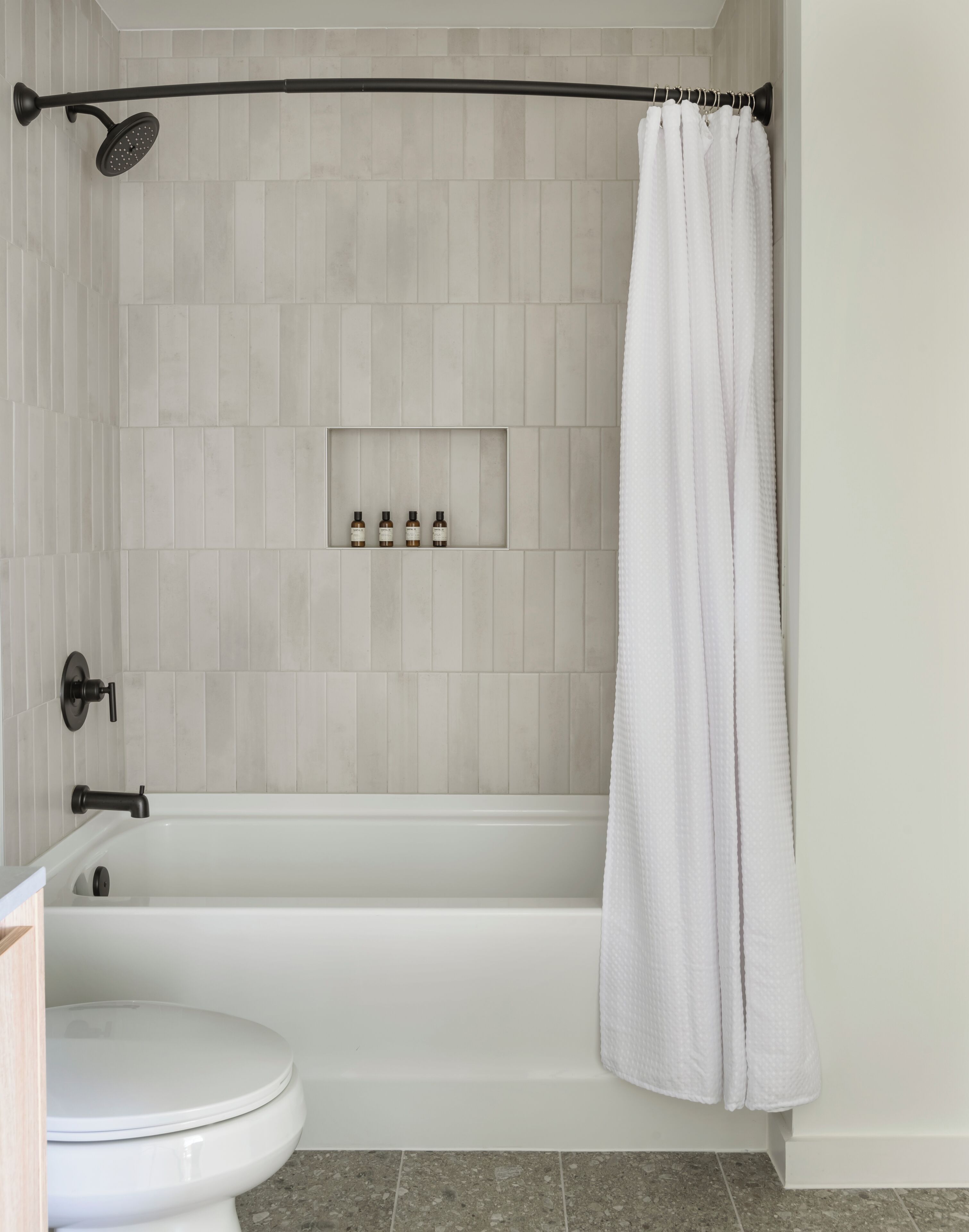 A bathroom with a bathtub, toilet, and a showerhead.