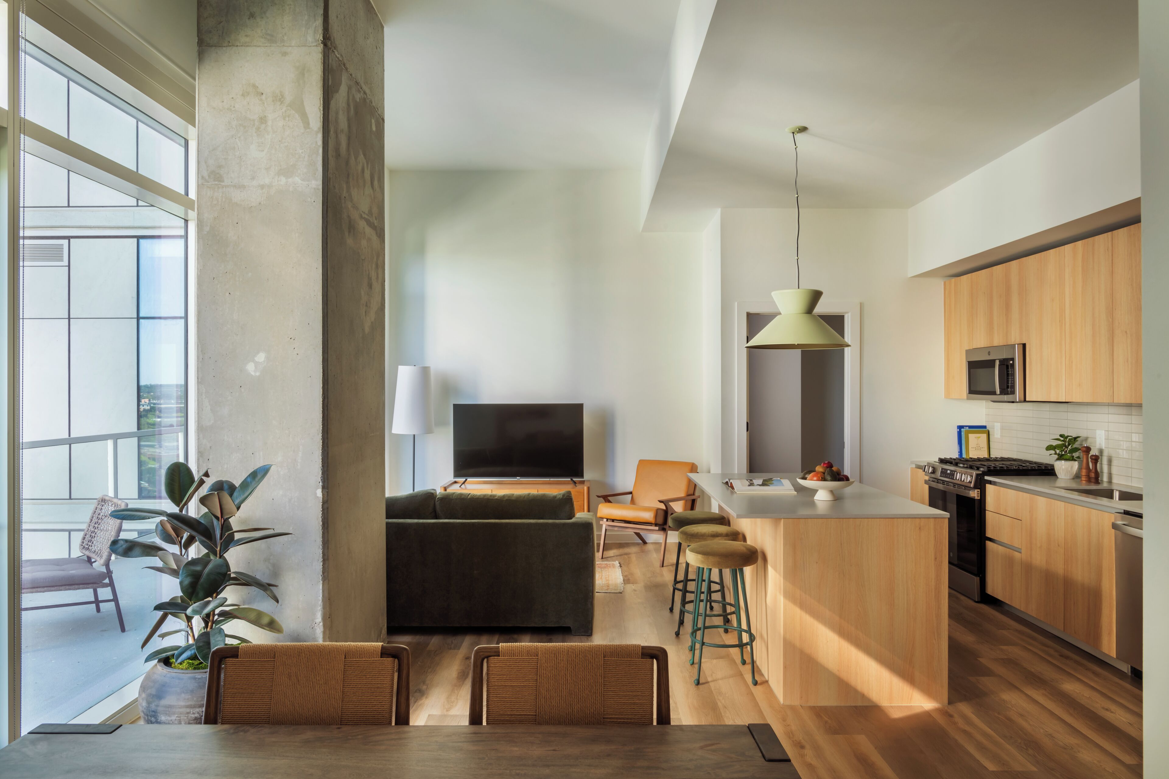 Una cocina moderna con armarios de madera, una isla central y una zona de comedor con mesa y sillas.