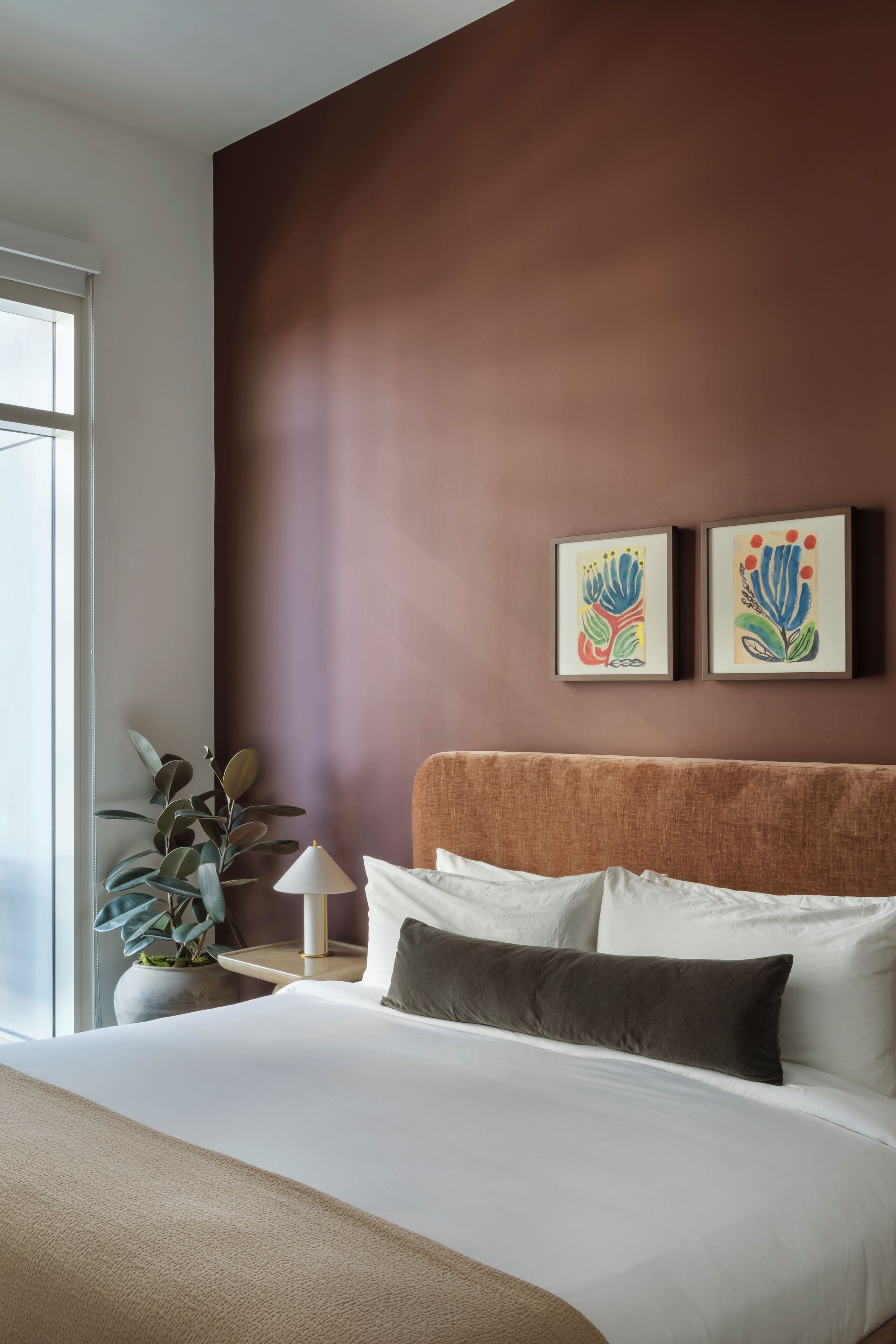 Habitación de hotel moderna con una cama grande, una mesita de noche, una lámpara y dos cuadros enmarcados en la pared.