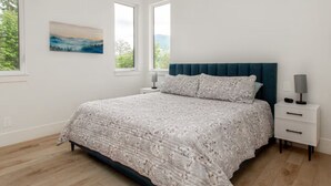 Une chambre à coucher avec un grand lit, une table de chevet, une lampe et un tableau au mur.