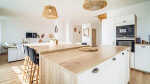 Een moderne keuken met witte kasten, een houten eiland en een inbouwoven.