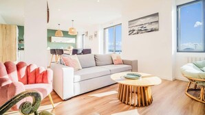Een moderne woonkamer met een bank, een rond bijzettafeltje en een eethoek met stoelen en een tafel.