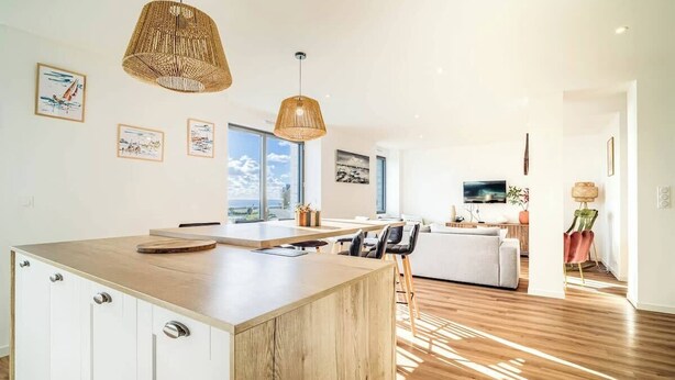 Een moderne keuken met een houten kookeiland, hanglampen en kunstwerken aan de muren.