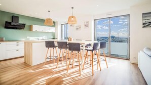Een moderne keuken met een centraal eiland, barkrukken en hanglampen.