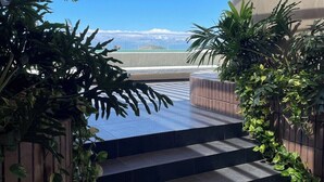 A staircase leading to a terrace with a view of a mountain range.