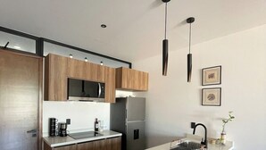 Eine moderne Küche mit Holzausstattung, einer Mittelinsel, Edelstahlgeräten und Pendelleuchten.
