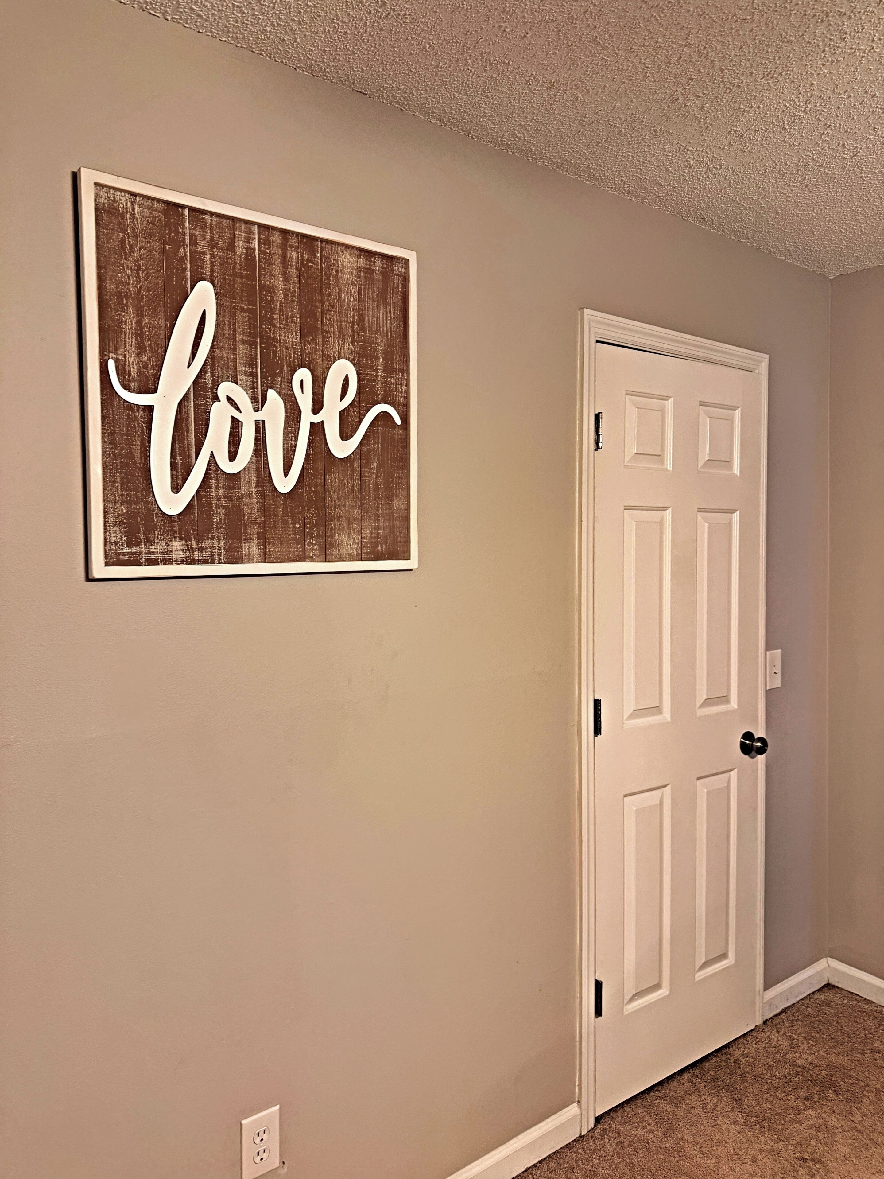 Un pasillo con una puerta y un letrero en la pared que dice 'love'.