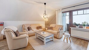Ett modernt vardagsrum med en soffgrupp, ett soffbord och en hängande lampa.
