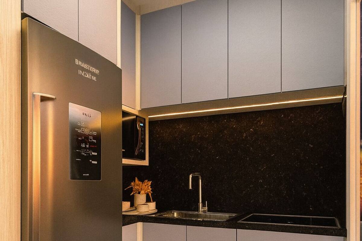 A modern kitchen with a stainless steel refrigerator, grey cabinets, a black countertop, and a marble floor.