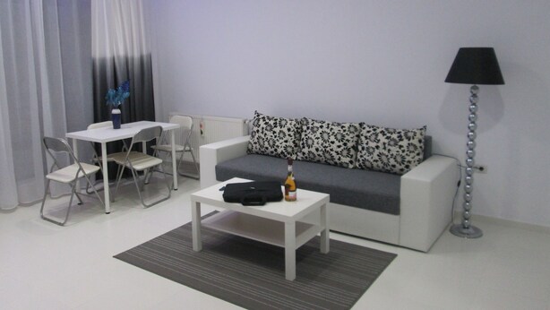 En moderne stue med en hvid sofa, et lille hvidt bord og en gulvlampe.