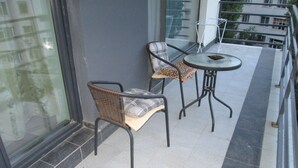 En balkon med to fletstole og et lille rundt bord, der viser udsigt over bybilledet.
