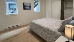 Ein Schlafzimmer mit einem Bett, einem Nachttisch, einer Lampe, einem Fenster und einem Kleiderschrank.