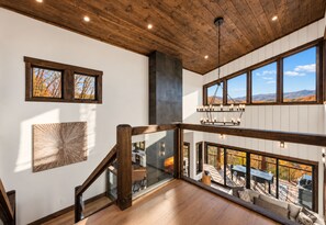 Ein mehrgeschossiges Interieur mit Holzbalken, einer Treppe und Blick ins Freie.