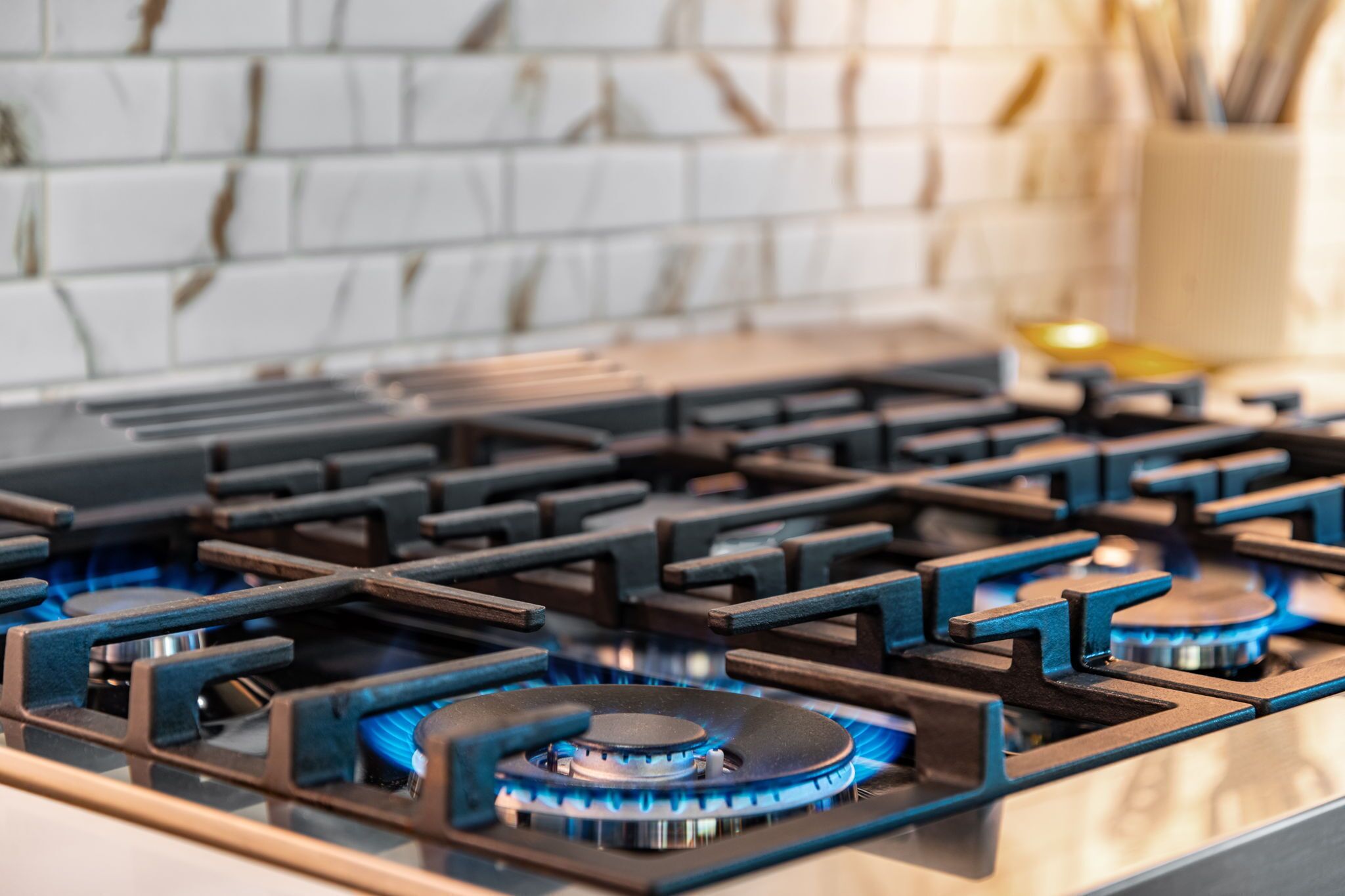 A kitchen with a gas stove and a tiled backsplash.