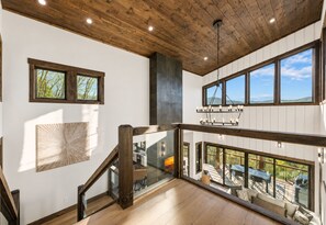 Ein mehrgeschossiges Interieur mit Holzbalken, großen Fenstern und einer Treppe.