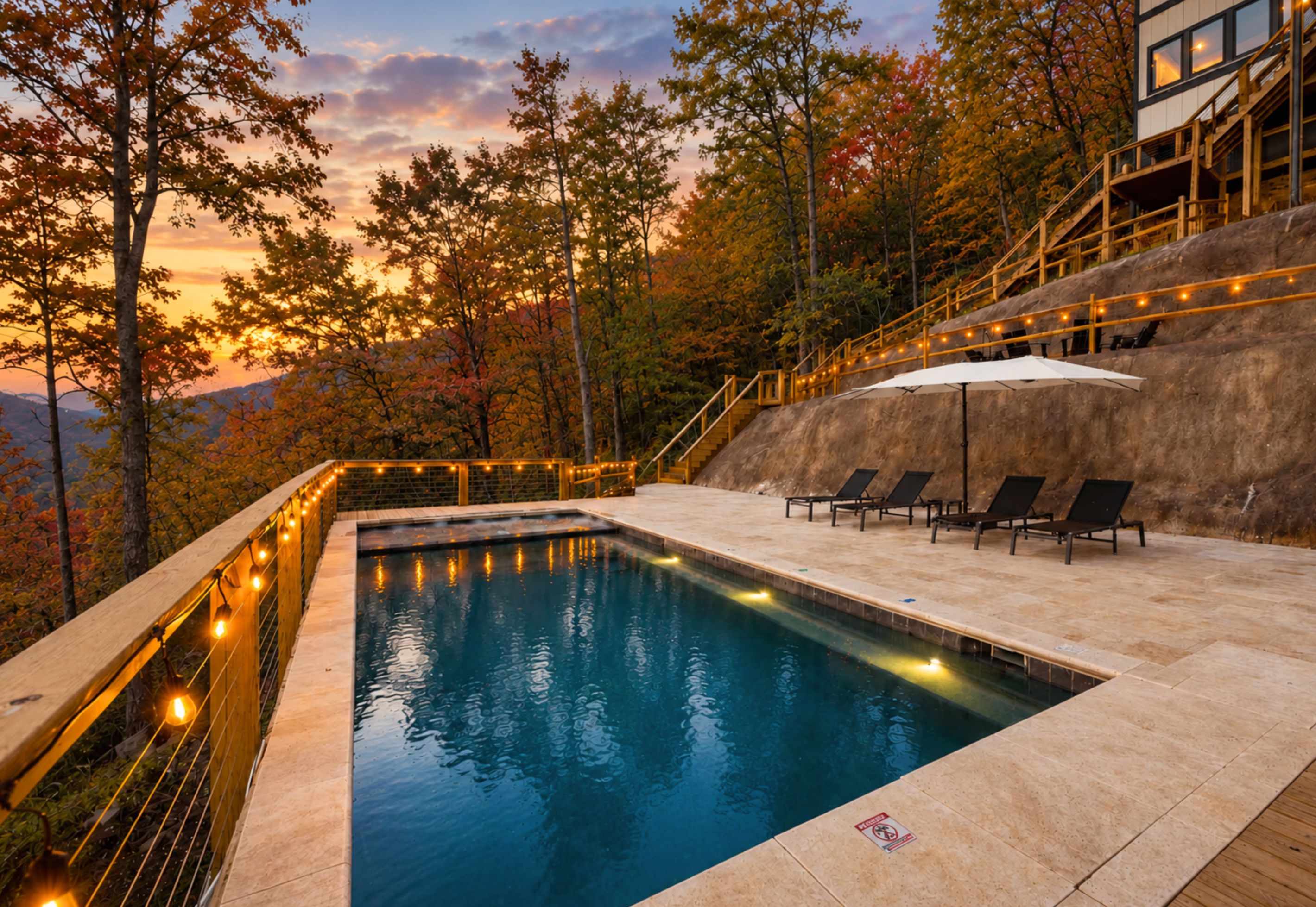 Une piscine avec vue sur les arbres et un coucher de soleil en arrière-plan.