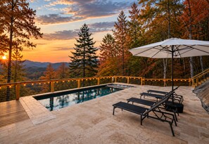 A swimming pool with lounge chairs and an umbrella, surrounded by trees and a sunset view. - Infinity Ridge: Elevated Pool Escape w/ Epic Views • Hot-Tub • Fire-Pit • Games (Epworth)