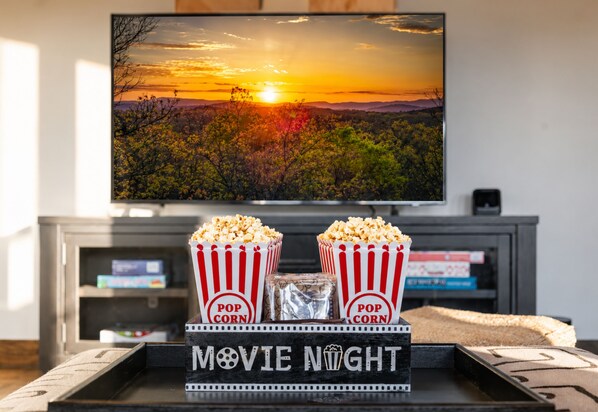 Un téléviseur à écran plat fixé au mur, un plateau avec des boîtes de pop-corn et une pancarte indiquant « SOIRÉE CINÉMA ».