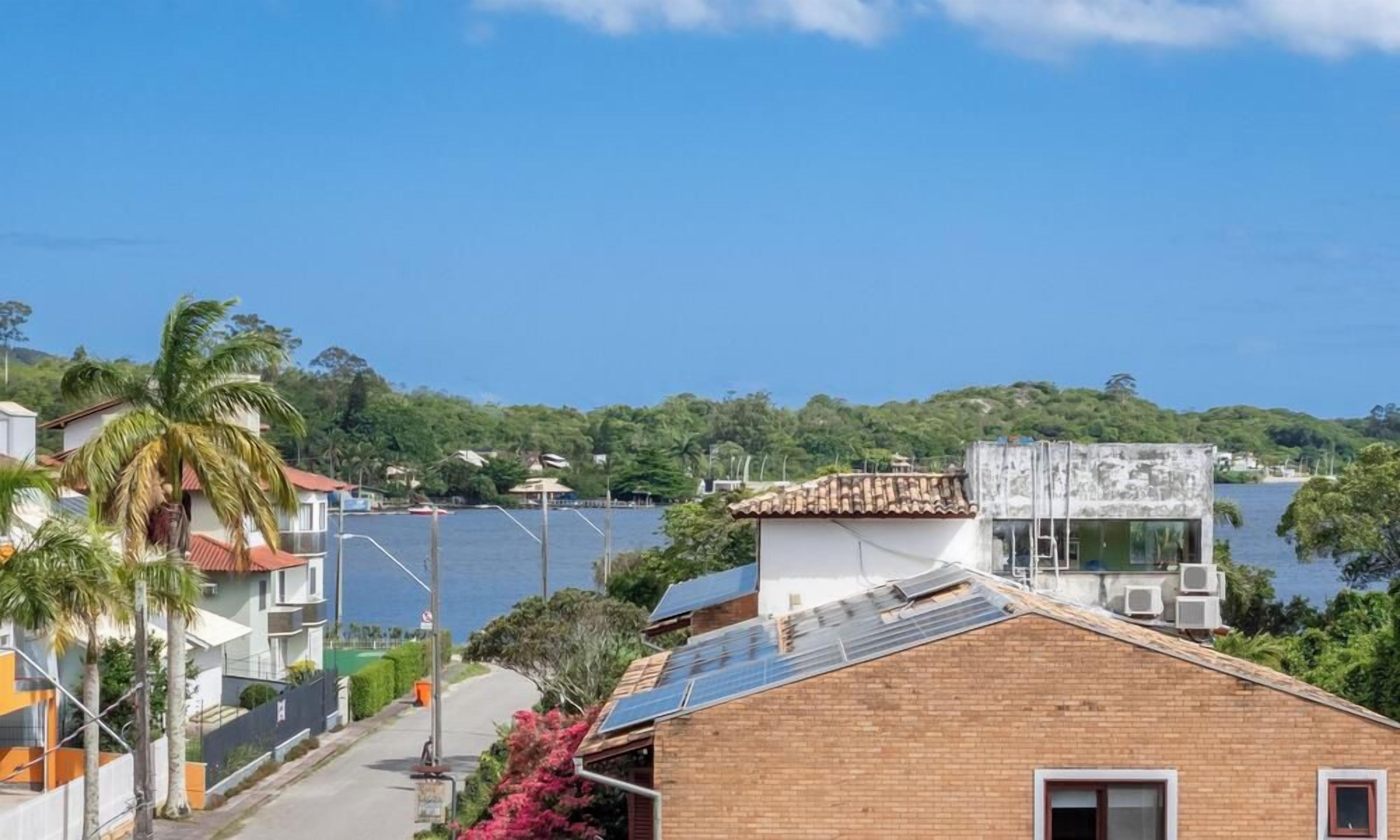 A coastal residential area with houses, a clear sky, and a body of water in the background.