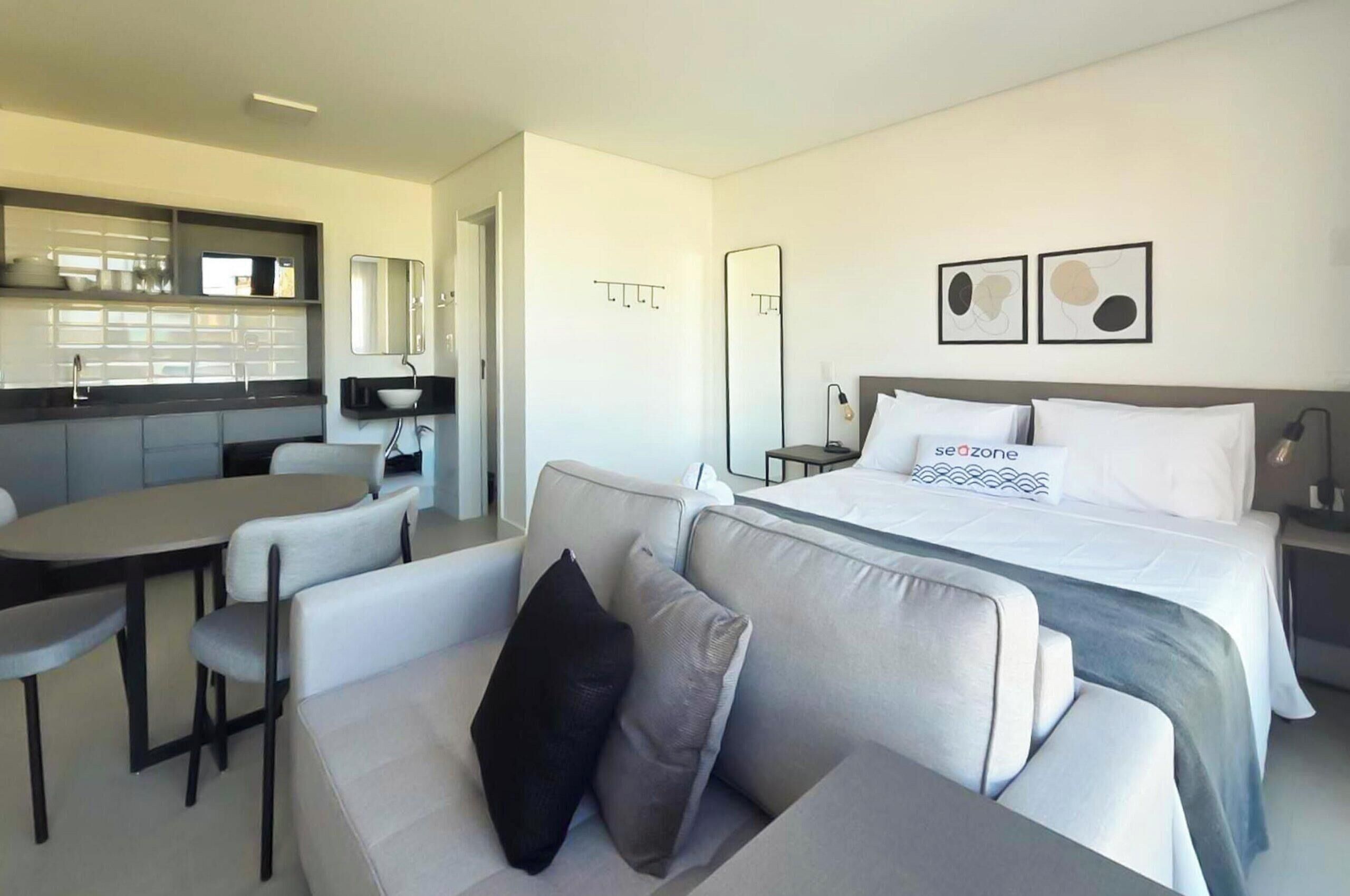 Een moderne hotelkamer met een bed, een bank, een eettafel en een kitchenette.