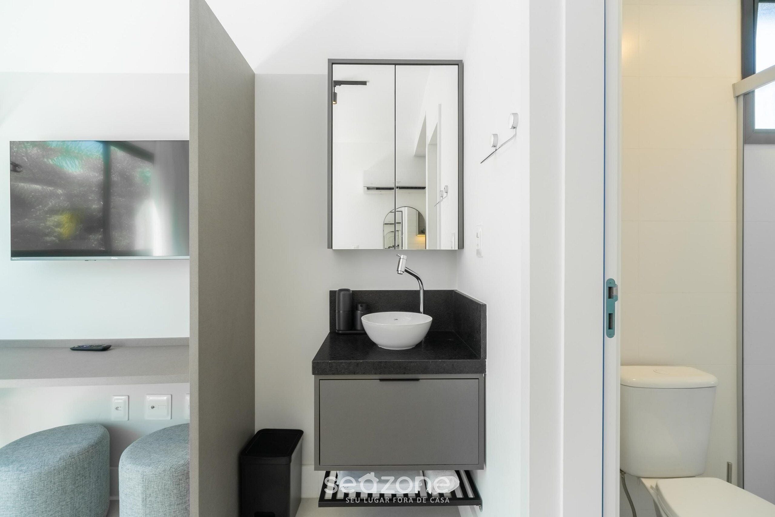 Un baño moderno con un espejo grande, un lavabo blanco y un inodoro.