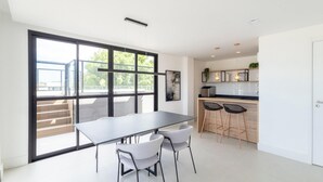 A modern kitchen with a large window, a dining area with a table and chairs, and a bar area with stools. - Modern Studios 150m From Lagoa da Conceicao - Lsts I (Florianópolis)
