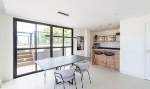 Uma cozinha moderna com uma janela grande, sala de jantar com mesa e cadeiras, e um espaço bar com banquetas.