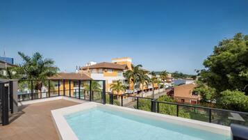 Una piscina en la azotea con vistas despejadas de edificios y palmeras circundantes.