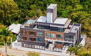 Uma casa moderna de vários andares, com piscina no terraço, janelas amplas e uma varanda.