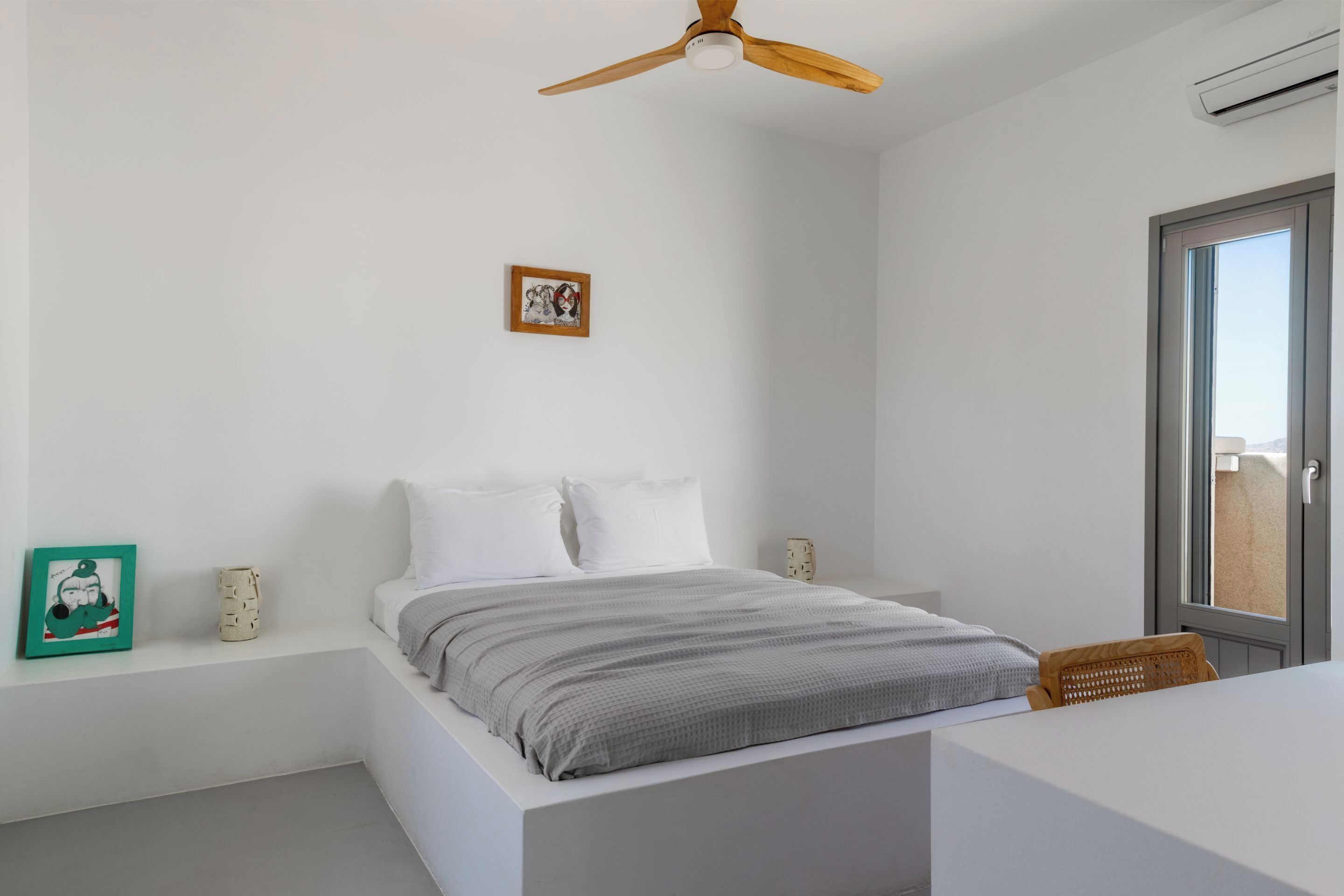 A bedroom with a bed, a ceiling fan, a window, and a wall-mounted air conditioner.