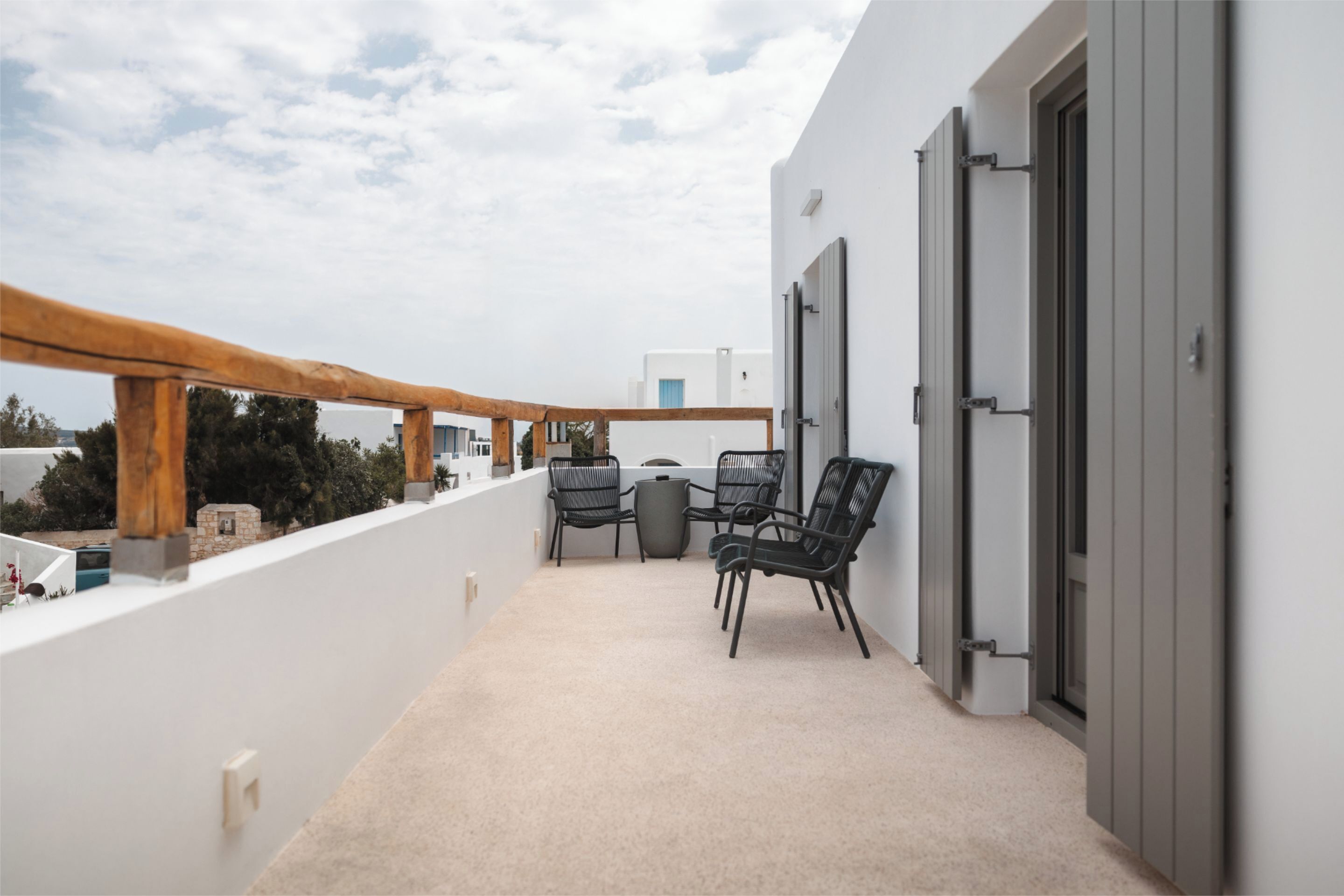 A balcony with a wooden railing, a table, and two chairs.