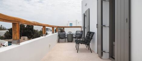 A balcony with a wooden railing, a table, and two chairs.
