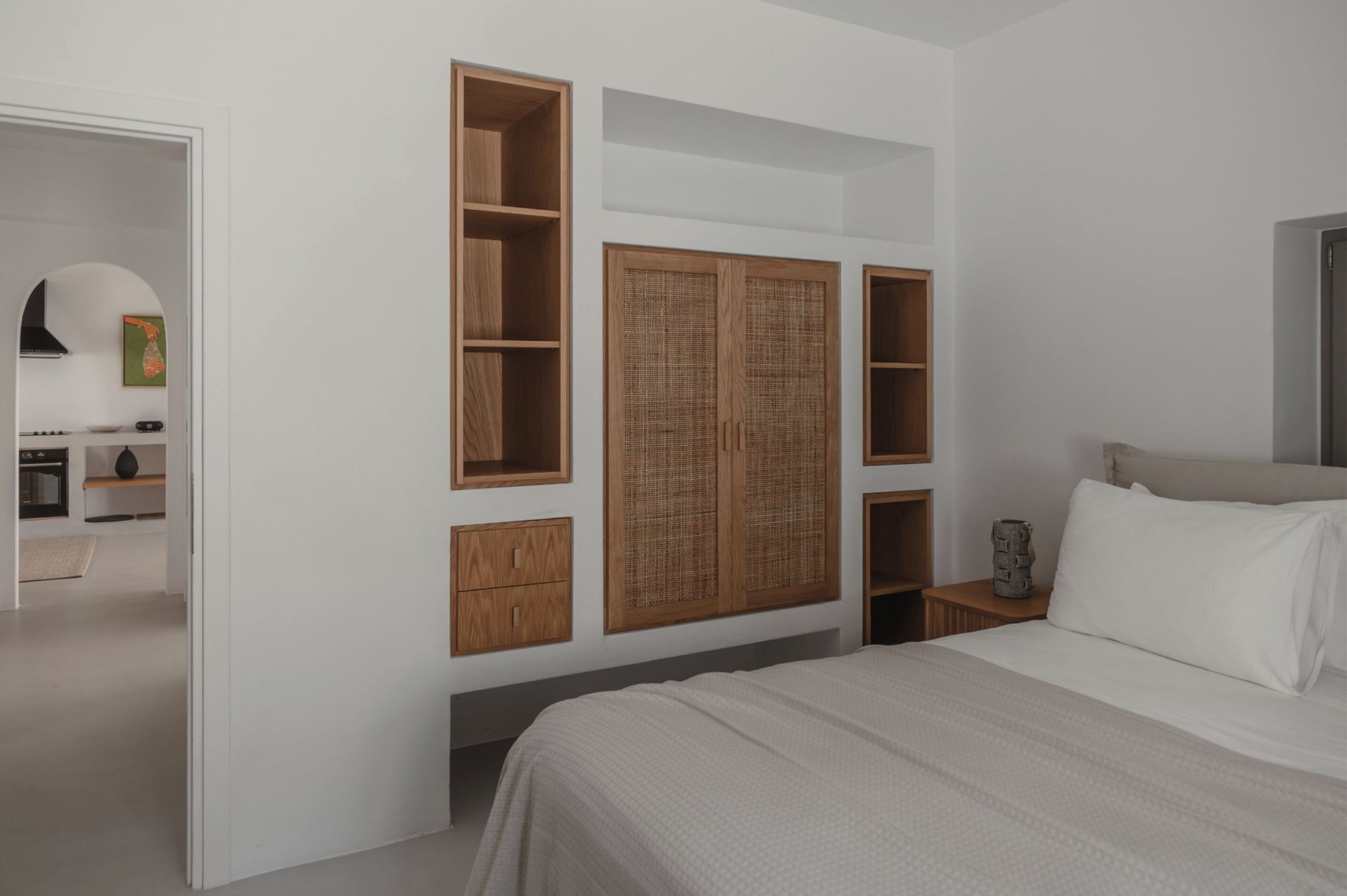 Ein Schlafzimmer mit einem Bett, einem Kleiderschrank mit offenen Regalen und einem kleinen Nachttisch.