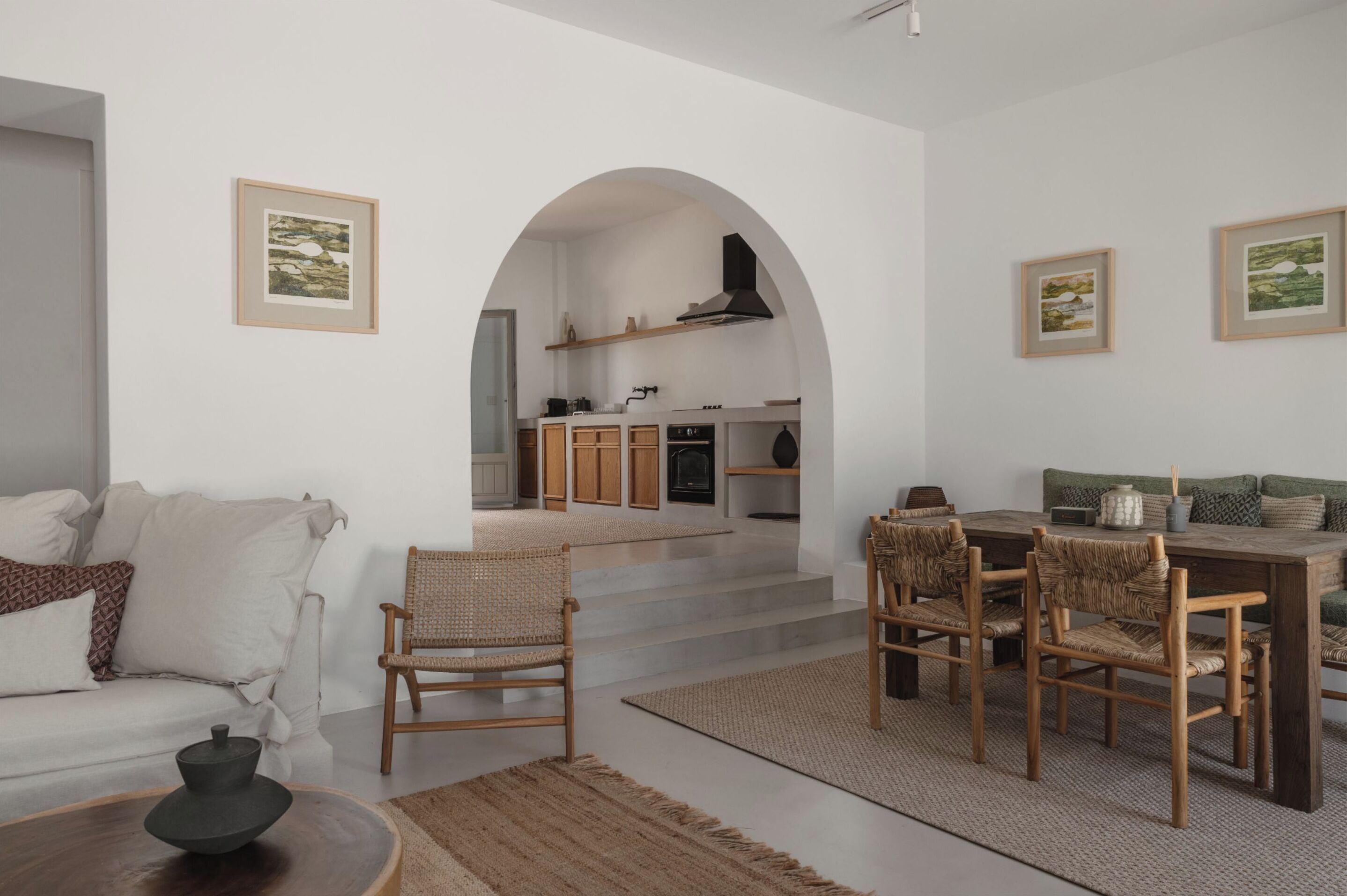 Un salon moderne avec un canapé, des fauteuils, une table à manger et une cuisine en arrière-plan.