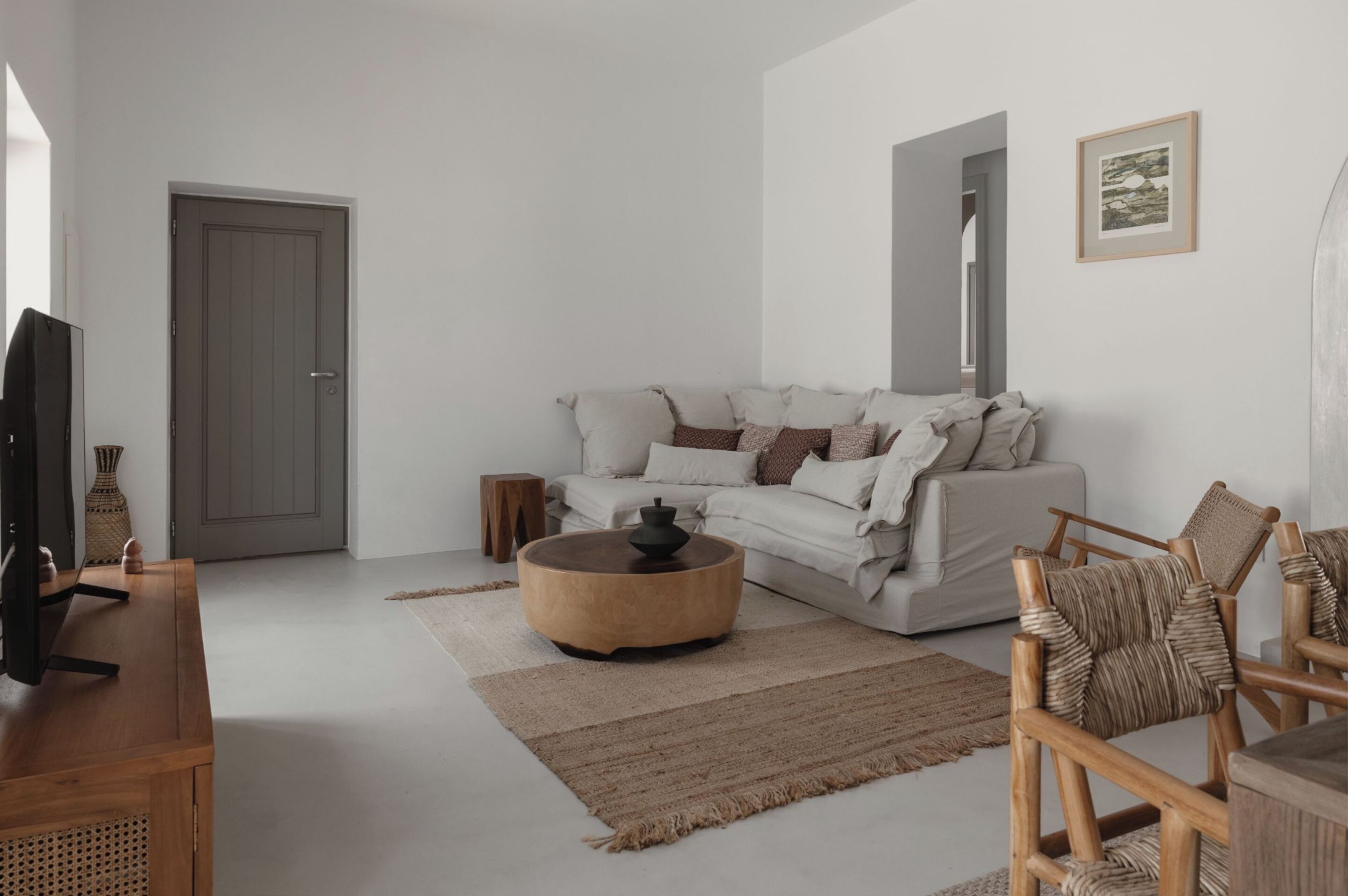 A modern living room with a white sofa, a round wooden coffee table, and a TV on a wooden stand.