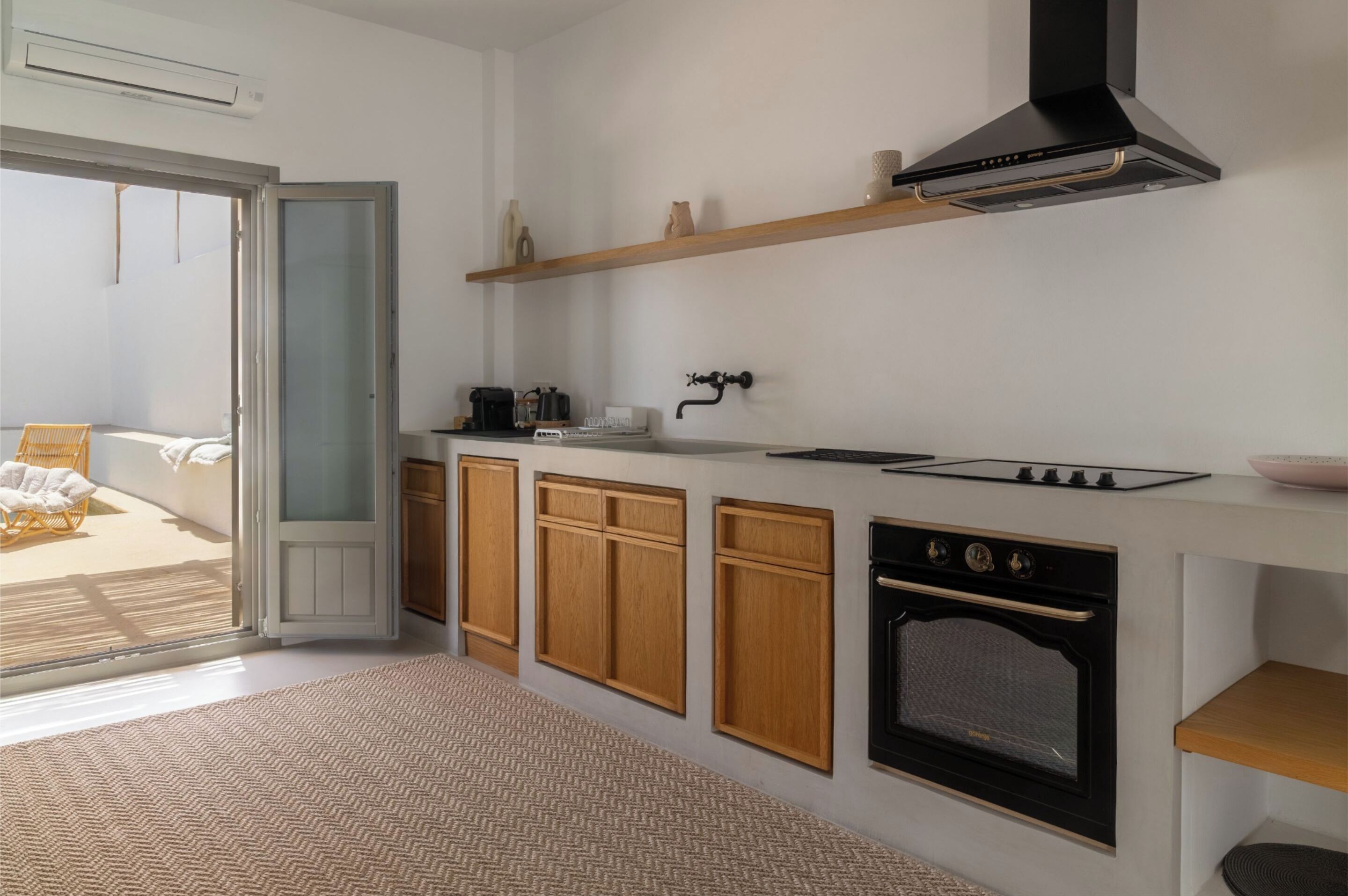 A modern kitchen with wooden cabinets, a built-in oven, and a black range hood.