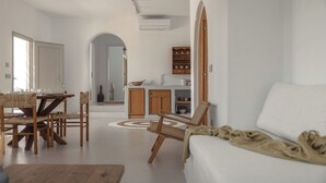 Ein geräumiger Wohnbereich mit Esstisch, einer Couch und einer Küche im Hintergrund.